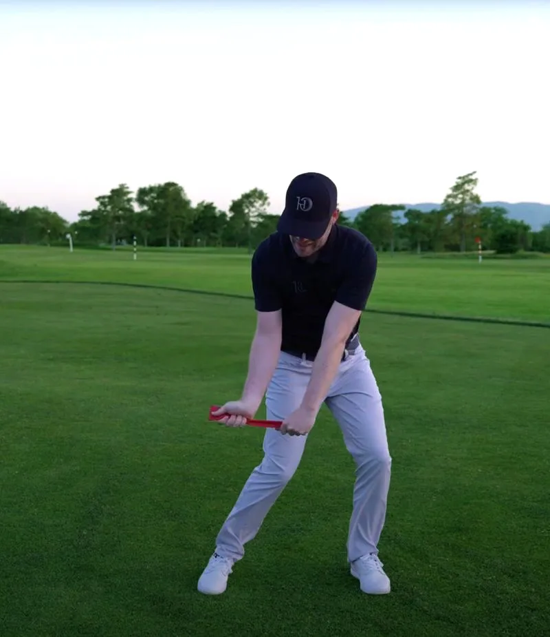 A golfer following along with a drill, alignment stick across the hips