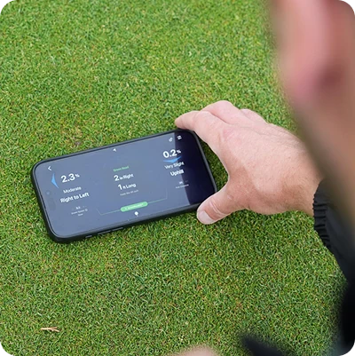 A phone resting on a putting green taking a slope reading