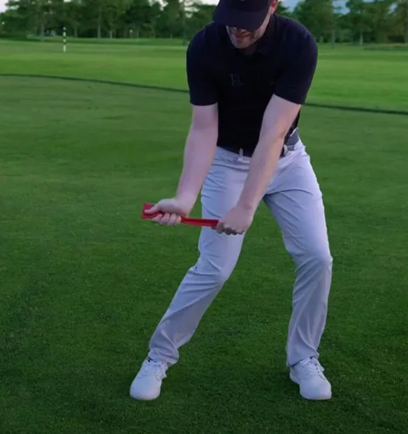 A golfer working through a drill with an alignment aid